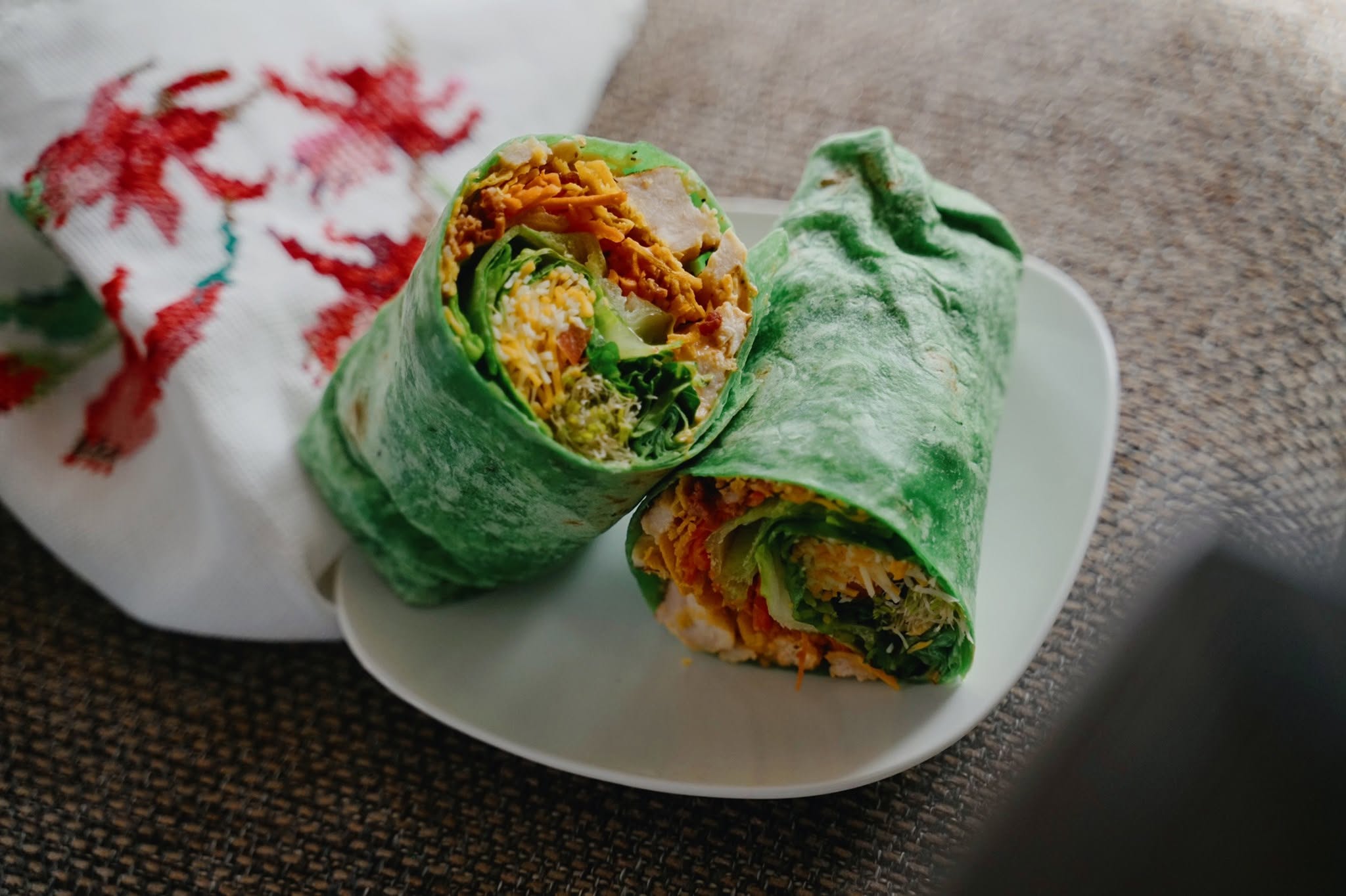 Spinach wrap cut in half, filled with chicken, cheese, greens and veggies